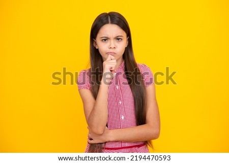 Smart nerdy school girl touching cheek and thinking against yellow background. Child think and idea concept. Thinking pensive clever teenager girl.
