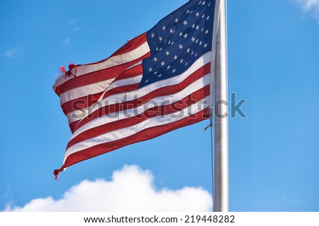 US American flag waving in the wind against blue sky and clouds