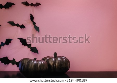 Black pumpkins and bat silhouettes on pink wall. Halloween party decor