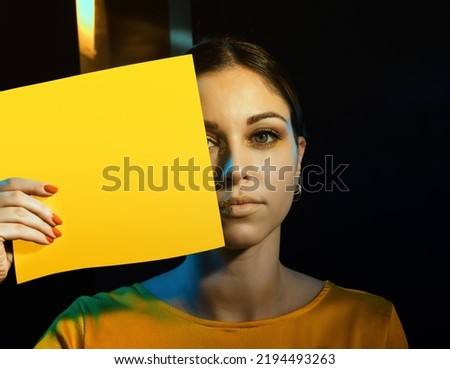 beautiful young woman showing a mockup yellow blank empty space. Mockup poster for message or photo. Copy space.