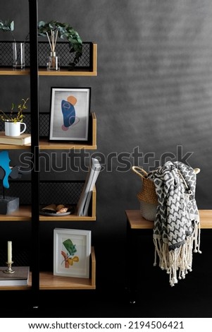 interior and home decor concept - book shelf with art and decorations over black background