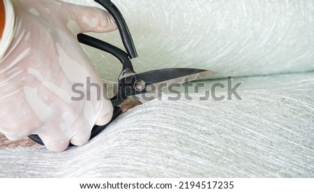 Fiberglass material cutting by scissors close up view Royalty-Free Stock Photo #2194517235