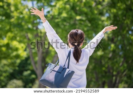 Japanese business woman taking a deep breath in the park Royalty-Free Stock Photo #2194552589