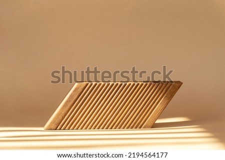 Geometric wooden stand with corrugated surface on brown background in rays of sunlight. Concept of 3d podium for presentation of cosmetic products, products.