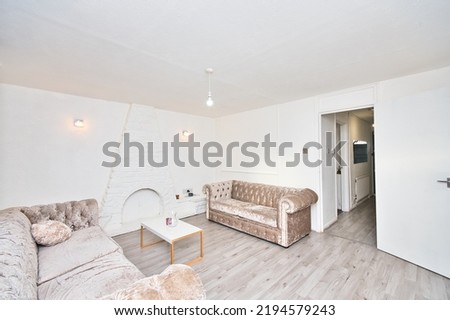Cosey Reception room with chesterfield sofa, laminated flooring, grey curtain, white walls, wall light, fire place in London UK