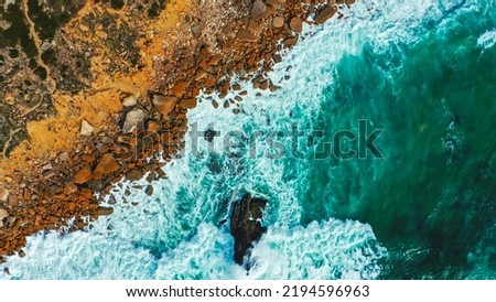 Drone view over  sea water surface the rocky shore. Top view over rolling ocean waves to the rocky shore.  Aerial view of the beautiful ocean and rocky shore with rolling waves on the summer day. Royalty-Free Stock Photo #2194596963