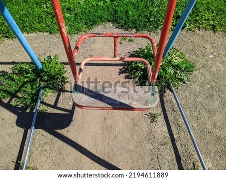 old broken swing on the playground during the daytime in summer. close-up photo