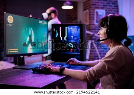Modern gamer streaming online multiplayer video games play on computer, enjoying shooting gameplay tournament. Female streamer playing action rpg game competition on pc monitor. Royalty-Free Stock Photo #2194622141