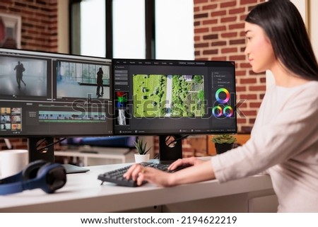 Asian graphic editor working on editing video and audio footage with professional software to create film content for post production. Using movie montage to edit multimedia movie.