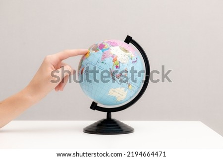 Globe of Ukraine on a white table. The index finger points to the globe. Close-up. Place for writing text.