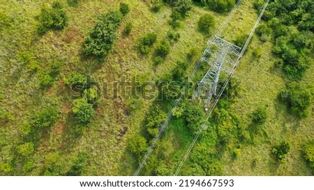Power pylons and high voltage lines in a mountainous Areaagricultural landscape. High-voltage masts. Electricity transmission power lines. 4K, UHD, Cinematic, Aerial footage Royalty-Free Stock Photo #2194667593