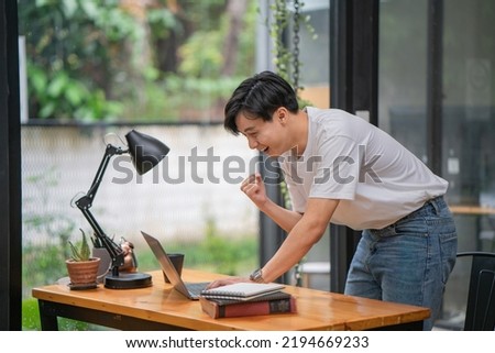 Happy young businessman works on laptop computer finish with excited and success on a desk at home, businessman using a notebook with achievement and surprise, freelance or employee. Royalty-Free Stock Photo #2194669233