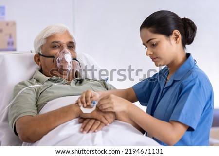 Female nurse injecting needle in hand of elderly patient at hospital
