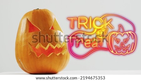 Neon trick or treat text banner with pumpkin icon over halloween pumpkins against grey background. halloween festivity and celebration concept