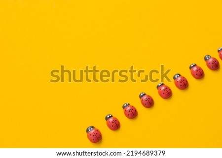 Colored wooden figures in the form of ladybugs on a yellow background