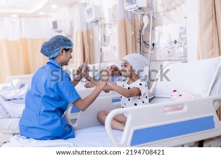 Little girl patient playing with nurse sitting on bed at hospital Royalty-Free Stock Photo #2194708421