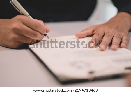 Businessman making agreement at office. it's a contract paper. Human hand holding pen mystery document on the table. It's a big decisions for business corporate.