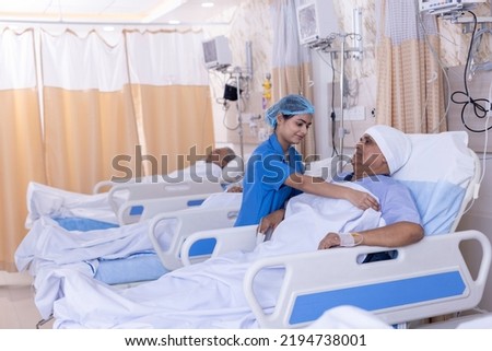Smiling nurse covering male patient on bed with blanket at hospital ward Royalty-Free Stock Photo #2194738001