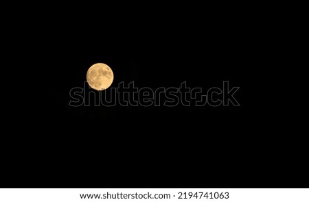 Full moon glows orange against deep black night sky