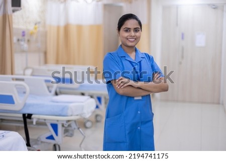 Portrait of smiling nurse wearing uniform standing at hospital ward