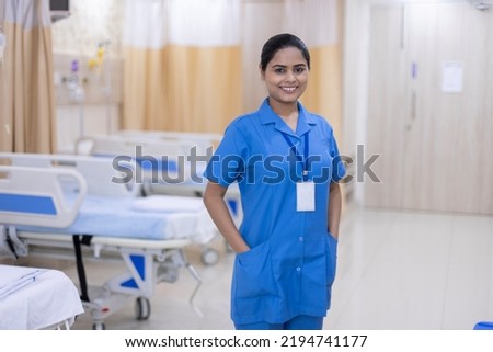 Portrait of smiling nurse wearing uniform standing at hospital ward