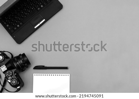 Top view of photojournalist concept with film camera, notepad and netbook on gray background. Royalty-Free Stock Photo #2194745091