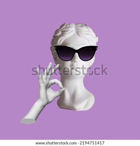 Confident antique female statue's head in black sunglasses shows the ok gesture with hand isolated on a purple color background. Trendy collage in magazine style. 3d contemporary art. Modern design