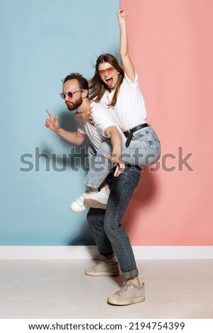 Youth. Young crazy man and astonished girl having fun isolated on blue and pink trendy color background. Human emotions, joy, enjoy, love and lifestyle concept