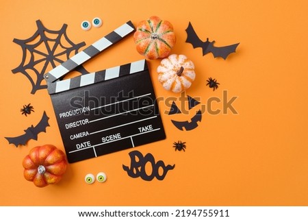 Horror movie night and Halloween party concept with   pumpkin, decorations and movie clapperboard on orange background. Top view, flat lay