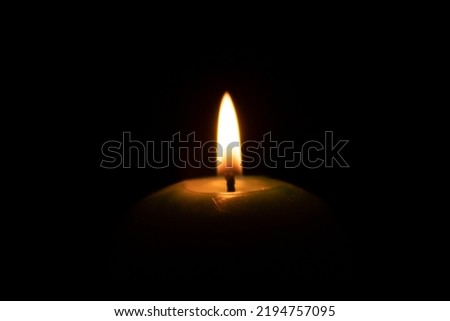 The candle flame and a blue candle on isolated black background
