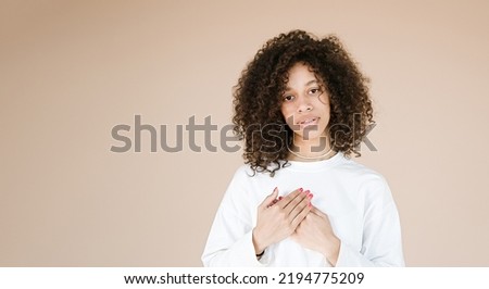Photo of cute attractive stylish lovely sweet african american girl crossing her hands on her chest smiling toothily enjoying life isolated over beige color background	                              