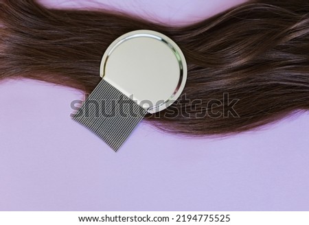 Lice comb and brunette hair on a violet background with copy space