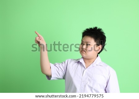 The Asian boy with student uniform on the green background.