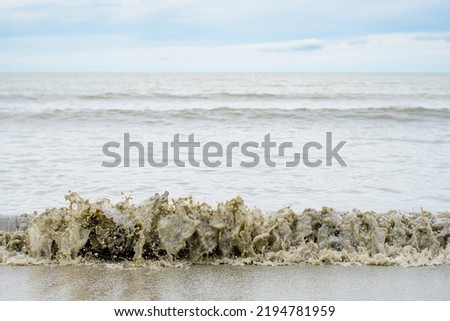 The sea and the beach are polluted with oil. A crude oil spill on the sand of a city beach. Beach oil spill impact, pollution, waste disposal. Ecological catastrophy
