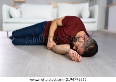 Unconscious Young Man Lying On Floor In Living Room Royalty-Free Stock Photo #2194798863