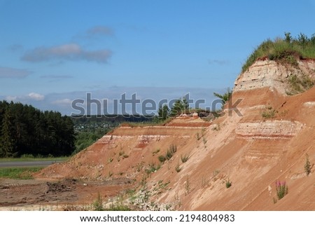 View of an old, grassy quarry. The village is in the background. Sovetsky district. Republic of Mari-El.