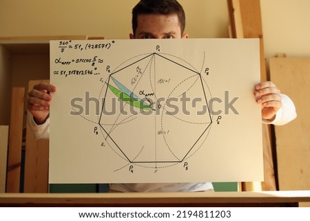 Young mathematician and designer Pavel Kubarkov and his drawing regular heptagon with green and blue colours on the paper in hands. Photo was taken 14 May 2022 year, MSK time in Russia.