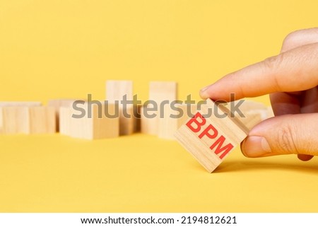 man hand chosen wooden block with text BPM on yellow background