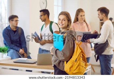 Portrait of smiling millennial Caucasian girl with backpack with groupmates in college or university. Happy young female schoolgirl satisfied with school course or training. Education concept. Royalty-Free Stock Photo #2194813343