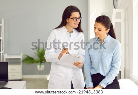 Medicine. Female doctor writes prescription or makes notes in female patient's card during medical examination. Friendly young nurse and woman talking in doctor's office in modern medical clinic. Royalty-Free Stock Photo #2194813383