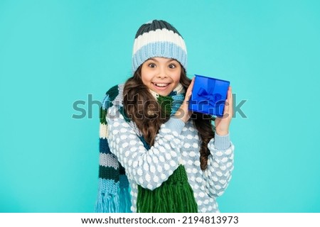surprised child in knitwear hold box. kid with present. teen girl on blue background.