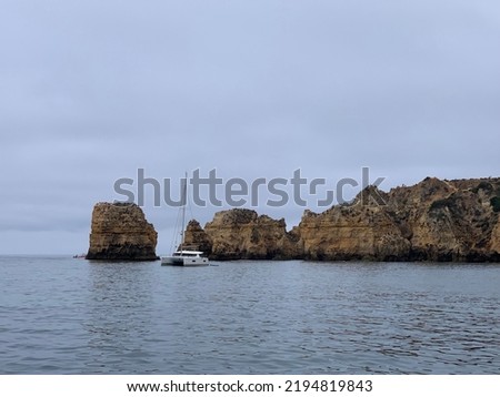 Aesthetic photography of the famous grottos and caves of Lagos, Algarve, with a white boat on a cloudy day
