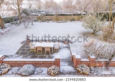 Large UK back garden covered in snow in winter. Snowy backyard scene