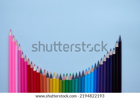 Many rainbow color pencils wave on blue background, flatlay. Multi colour pencils line for kids kindergarten elementary drawing classes preschool education top view, flat lay. Back to school concept