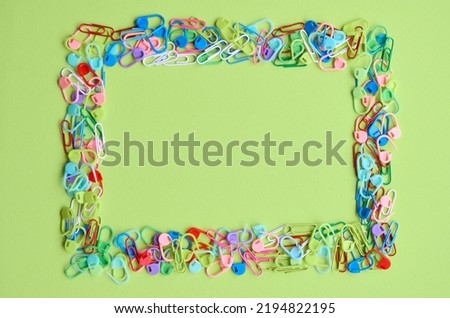 School supplies products multi colored fasteners frame isolated on green bright background, trendy flatlay, top view. Children education classes. Back to school concept. Copy space