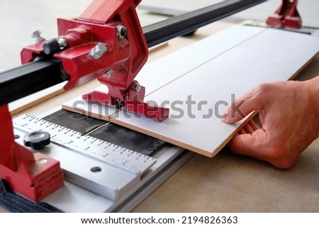 close-up of a work tool using manual cutting equipment for laying, processing ceramic tiles. Red tile cutter Royalty-Free Stock Photo #2194826363