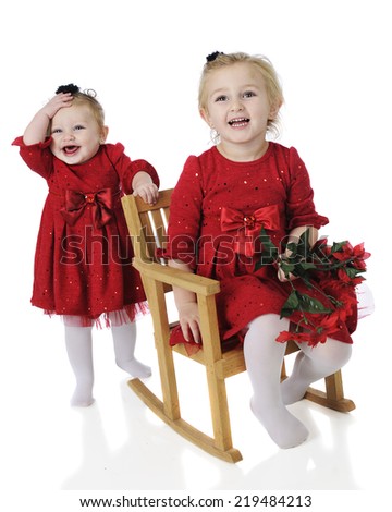 A preschooler and her baby sister all dressed up for Christmas.  Both are laughing in their identical red dresses.  On a white background.