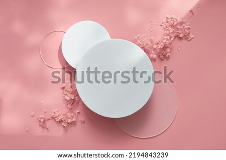 White round podium pedestal cosmetic beauty product presentation empty mockup on trendy pink coral pastel background with light shadows and spring flowers, minimalist flat lay backdrop, top view. Royalty-Free Stock Photo #2194843239