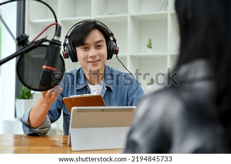 Professional and talented young asian male radio host enjoy discussing and interviewing his female special guest during the podcast show in the studio.