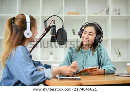 Happy and cheerful young Asian female radio guest enjoys talking with a professional female radio host in the studio. podcast and broadcast concept.